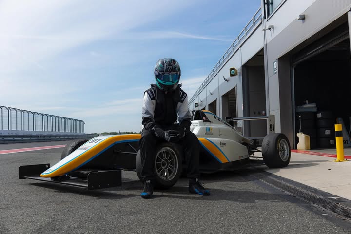 Alex kierowca wyścigowy w tle bolid Formuły 4 (F4) na torze wyścigowym w sekcji pit stop